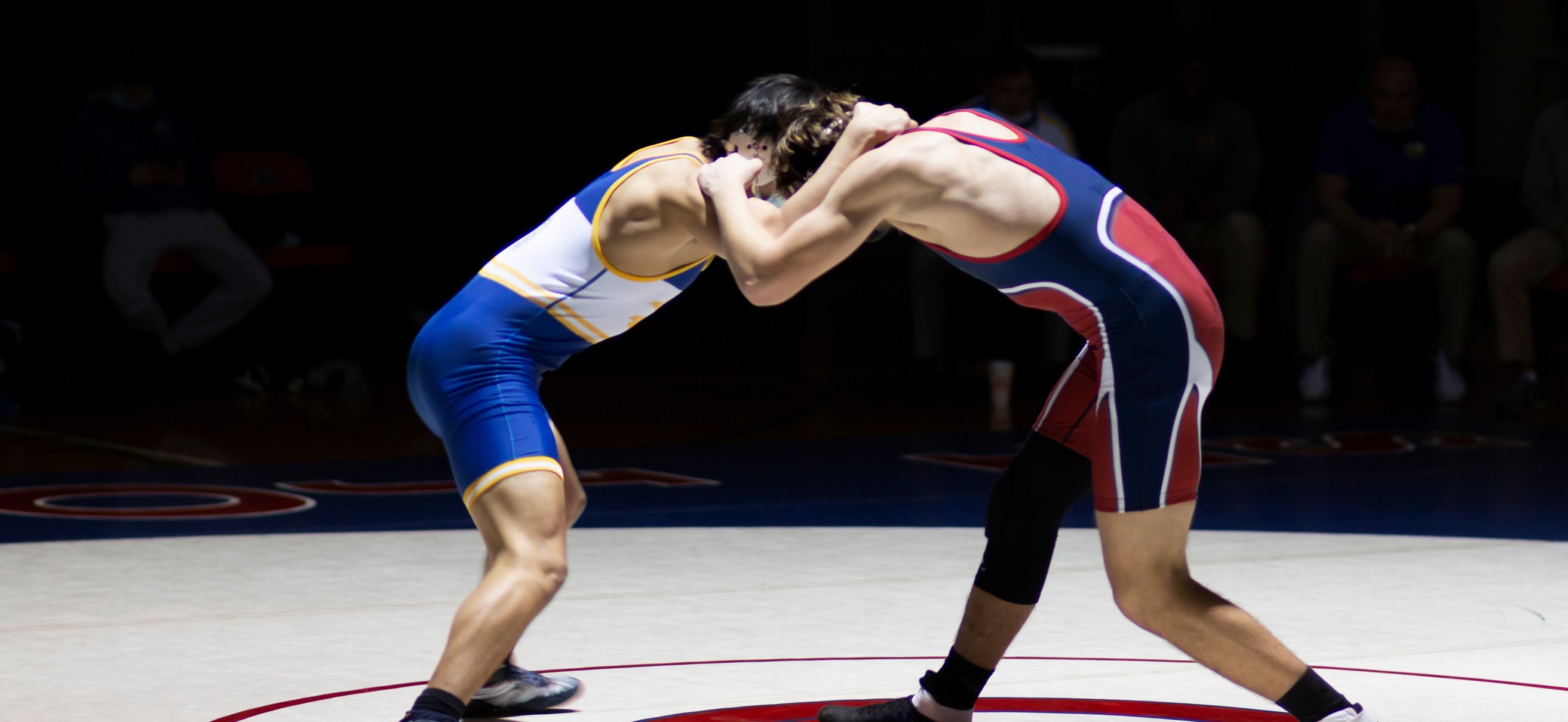 Two wrestlers have each other arms locked around the others head